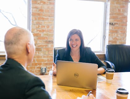Dos personas sentadas en una mesa hablando en una empresa de consultoría tecnológica.