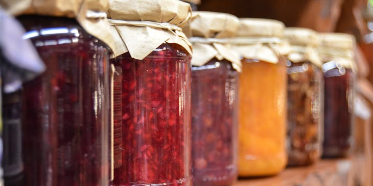 A shelf filled with various jars of jams.