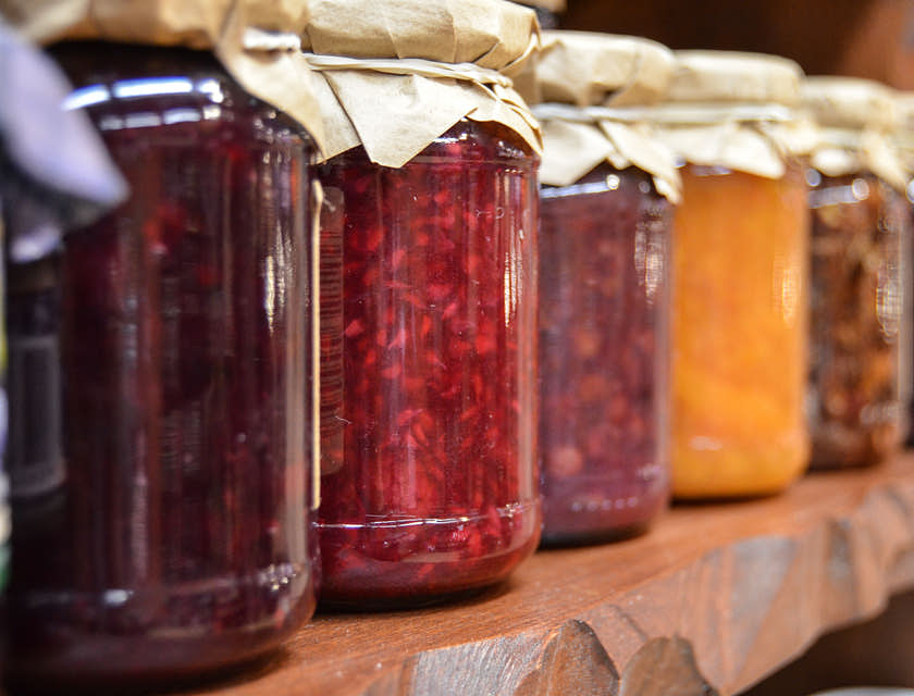 Diversi barattoli con confettura di frutta esposti su una mensola.