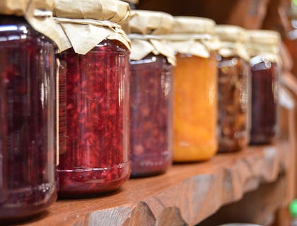 A shelf filled with various jars of jams.