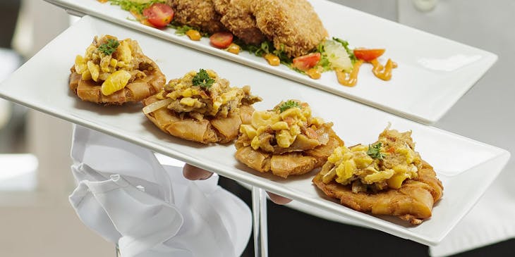 Chef with food typical to Jamaican restaurants.