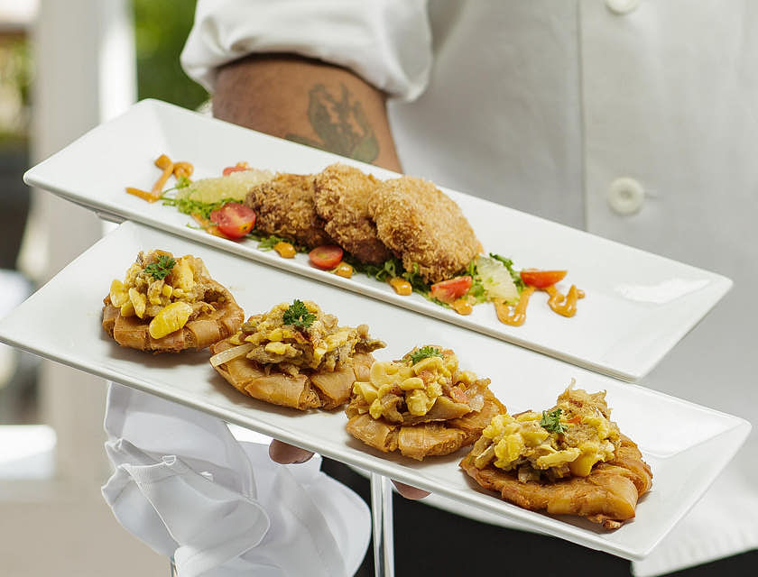 Chef segurando pratos de comida típica jamaicana.
