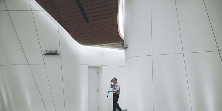 A janitor mopping the floor in front of a white door.