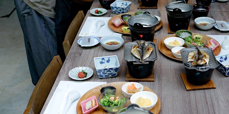 Mesa posta com tigelas, peixe grelhado e acompanhamentos em um restaurante japonês.