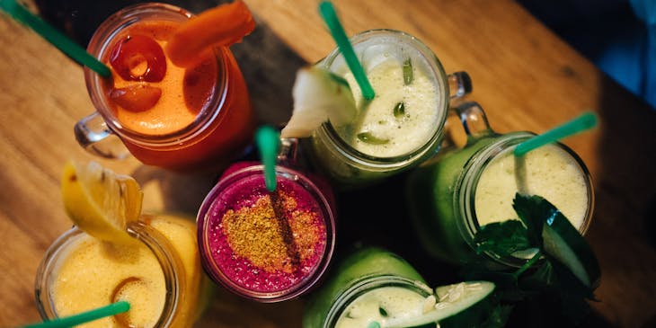 A variety of drinks in mason glass jars on a dark wood background