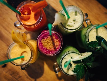 A variety of drinks in mason glass jars on a dark wood background