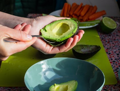 Una persona saca un aguacate de su cáscara.