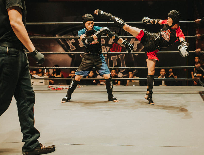 Dos hombres practicando kickboxing en un ring en un negocio de kickboxing.