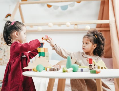 Duas crianças brincando com blocos em um quarto infantil.