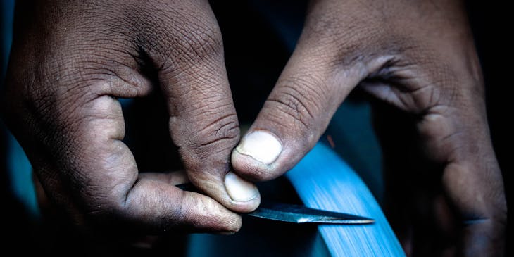 A man sharpening a knife on a grinding wheel.