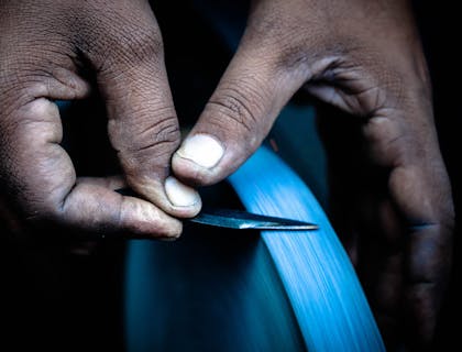 A man sharpening a knife on a grinding wheel.