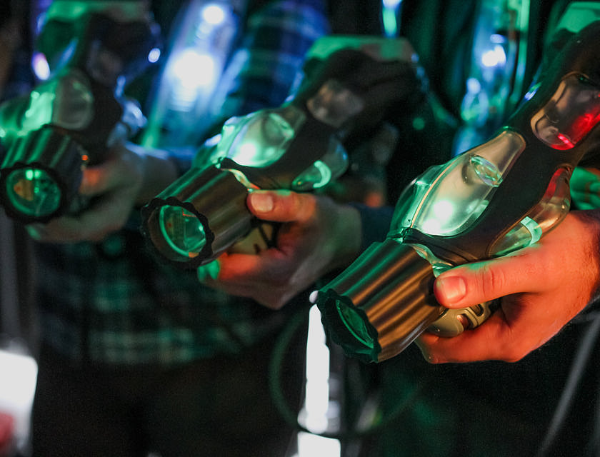 Delle persone che tengono in mano delle armi da laser tag nere e verdi.