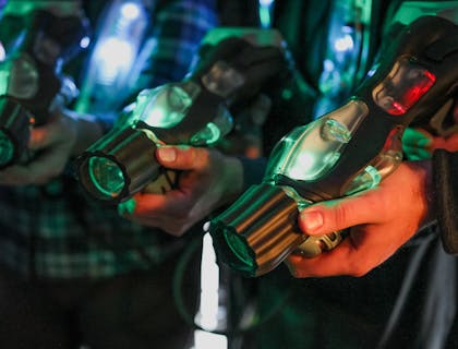 Personas sosteniendo pistolas láser color verde y negro en un negocio de laser tag..
