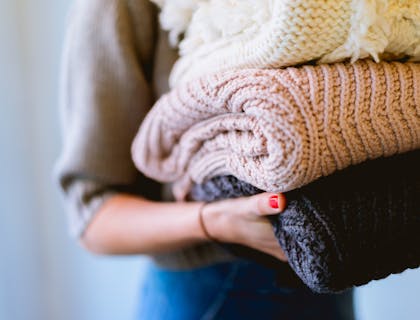 A laundry service worker holding freshly folded clothes.