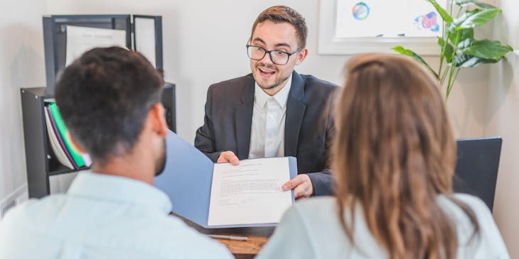 Un employé d'un cabinet d'avocats remettant un contrat à des clients.