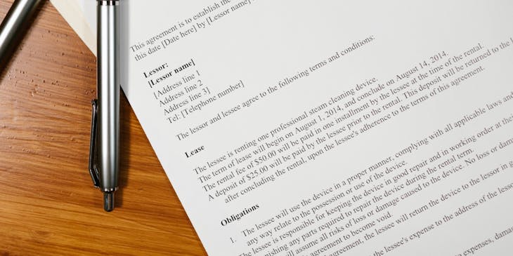Two pens and a lease agreement on a table.