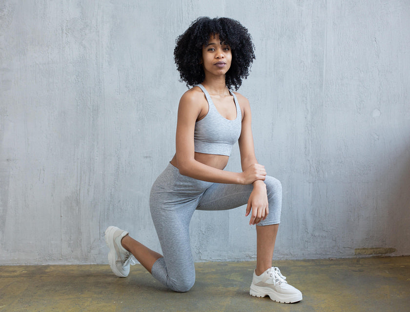 Une personne en leggings gris posant sur un genou.