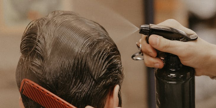 Une personne se fait pulvériser du liquide sur les cheveux dans une entreprise de traitement des poux.