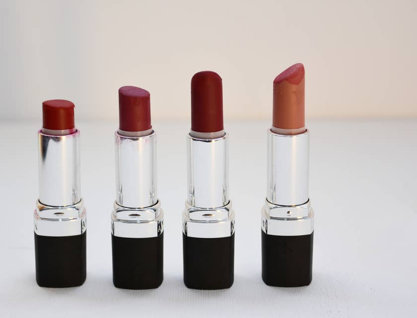 Quatre rouge à lèvres sur un présentoir blanc dans un magasin.
