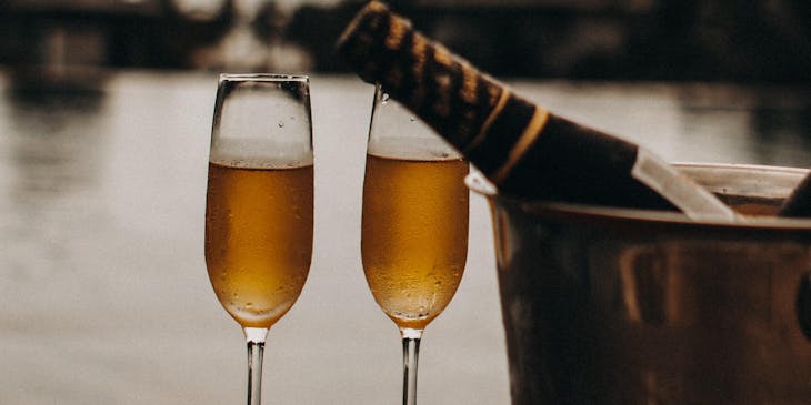 Two champagne glasses, an ice bucket, and a bottle of champagne provided by a luxury business.