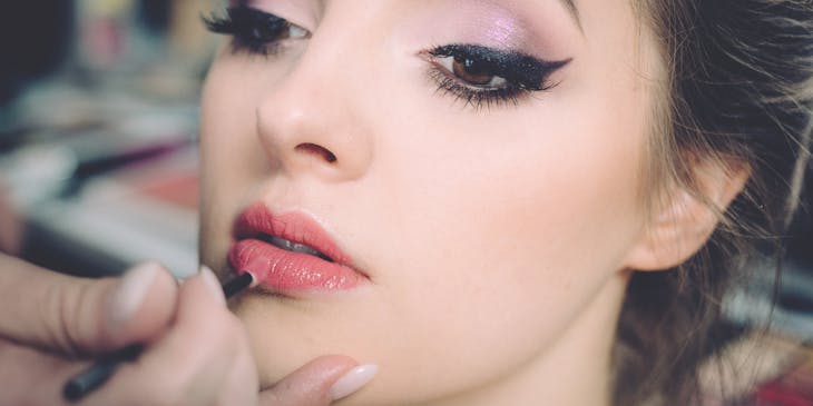 A woman having makeup applied by makeup artist.
