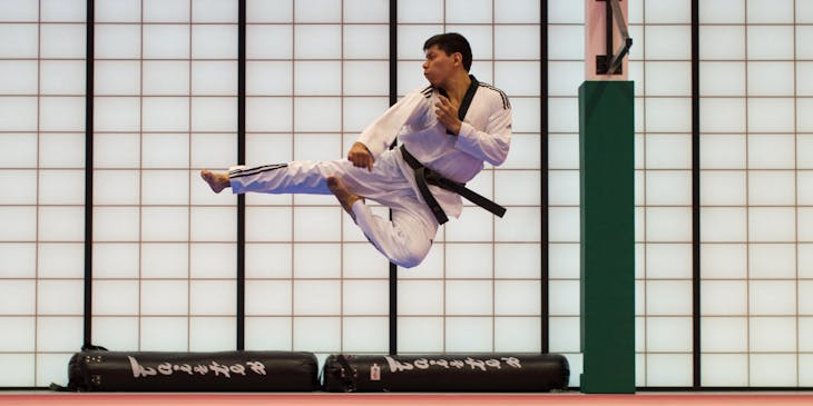 Man practicing martial arts by doing a flying kick.