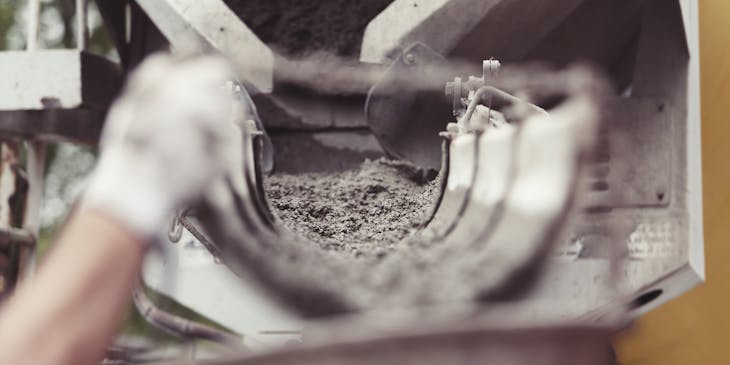 Concrete in a truck pouring out of a chute.