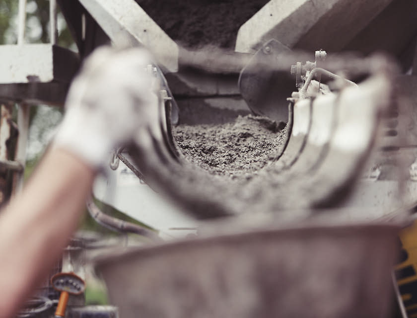 Ein Maurer lässt Beton über ein Rohr von einem Lastwagen in einen Behälter fließen.
