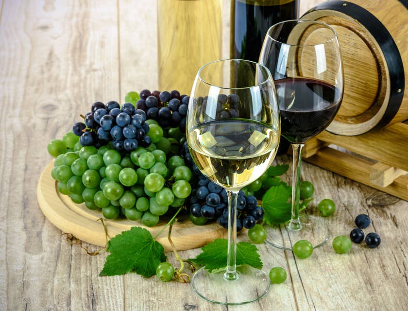Dei calici di vino con accanto dei grappoli di uva matura.