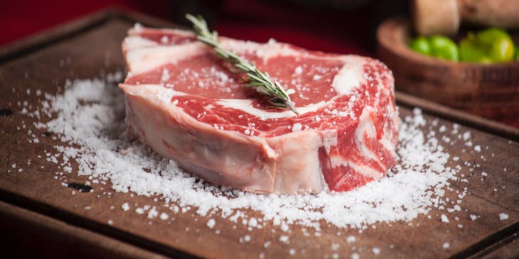 Large cut of meat with rosemary and salt in a meat shop.