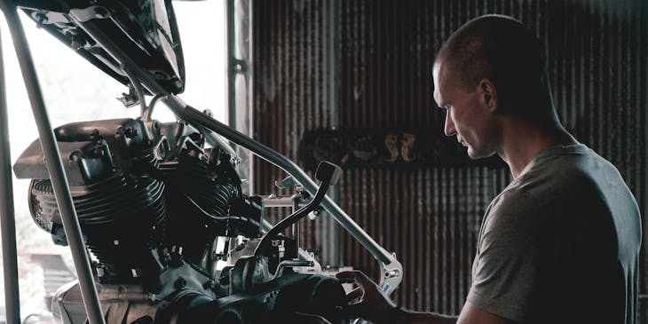 A mechanic working on a motorcycle in a mechanic shop.