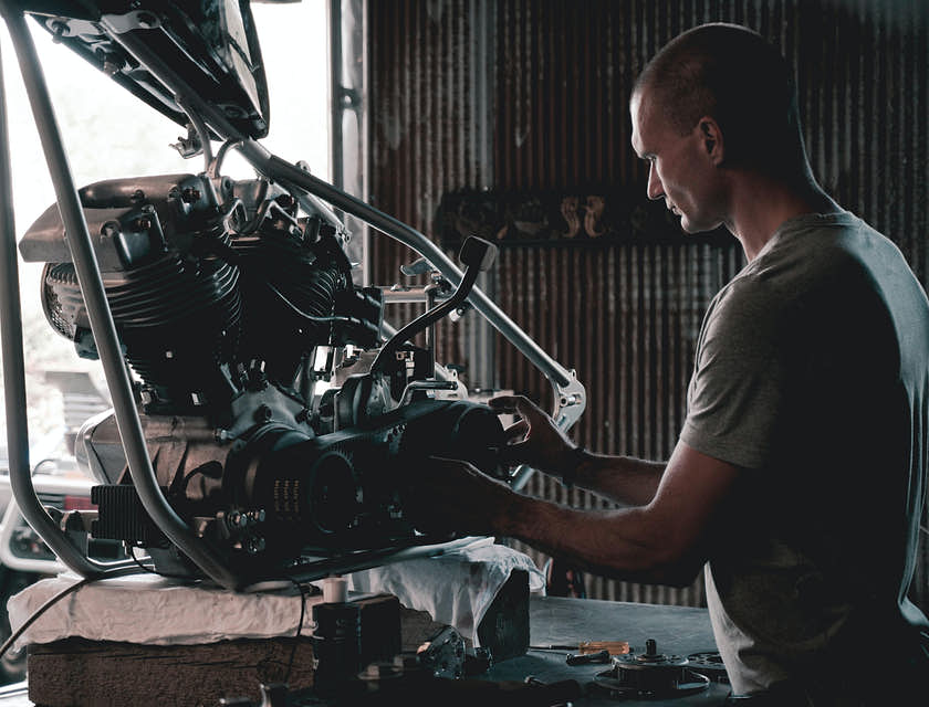 A mechanic working on a motorcycle in a mechanic shop.