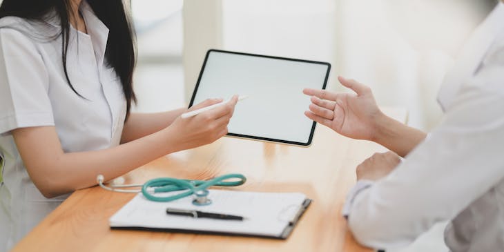 woman sitting with a stethoscope and tablet