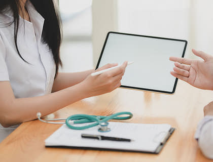 Une femme assise avec un stéthoscope et une tablette.