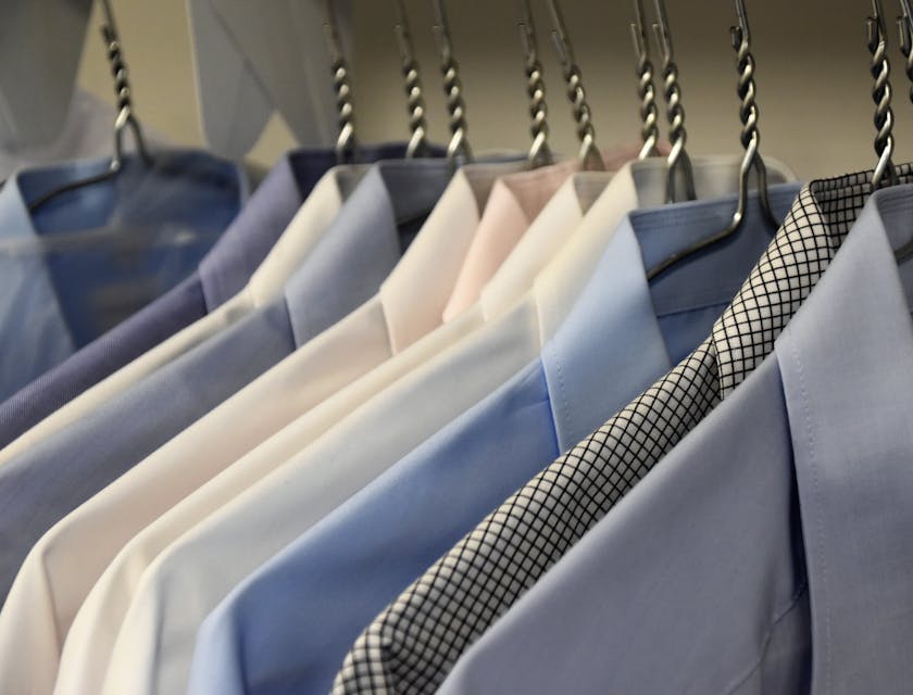 Camisas colgadas en ganchos en un negocio de ropa para hombre