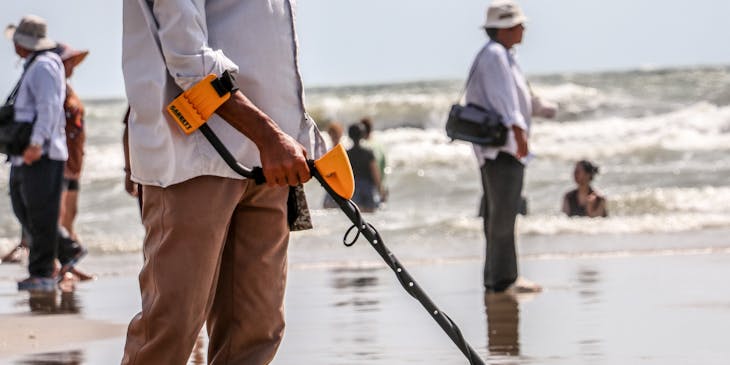 Man using metal detector at the beach.