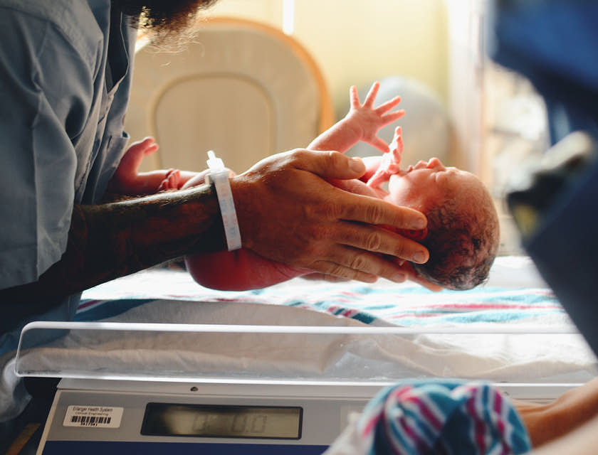 Un'ostetrica che tiene in mano un bambino appena nato.