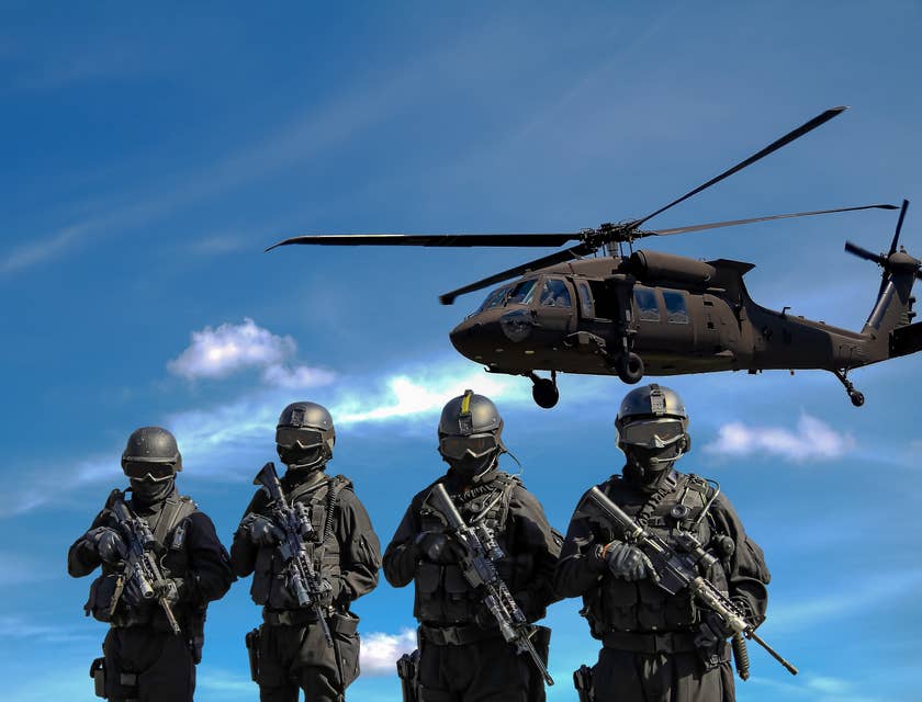 Four armored soldiers from the military carrying rifles with a helicopter in the background.