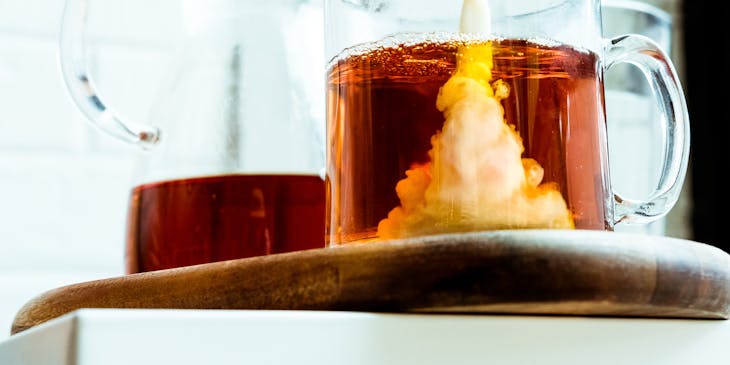 Person pouring milk into a cup of tea.