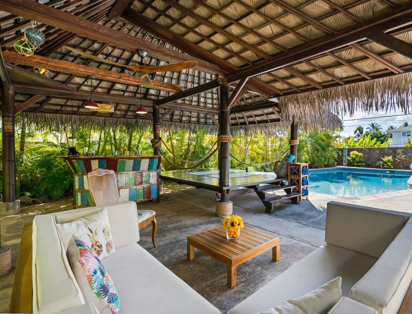 Un patio confortable avec des ventilateurs, des sièges, un bar et une piscine.