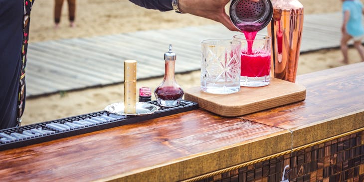 A bartender pouring a drink on a beach.