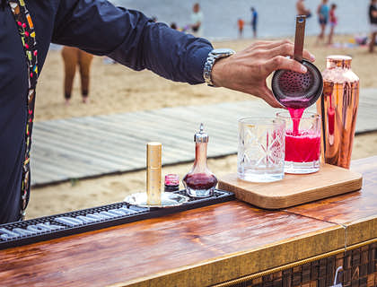 A bartender pouring a drink on a beach.