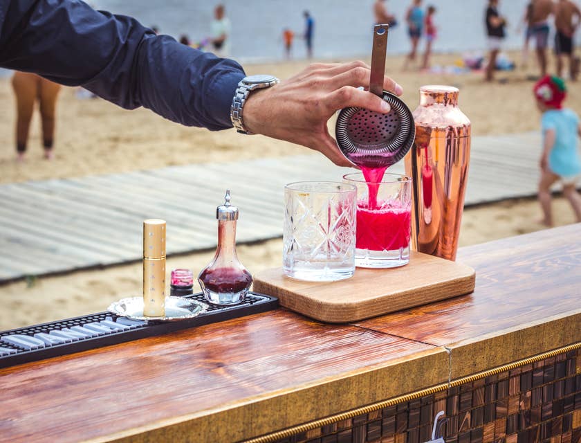 A bartender pouring a drink on a beach.