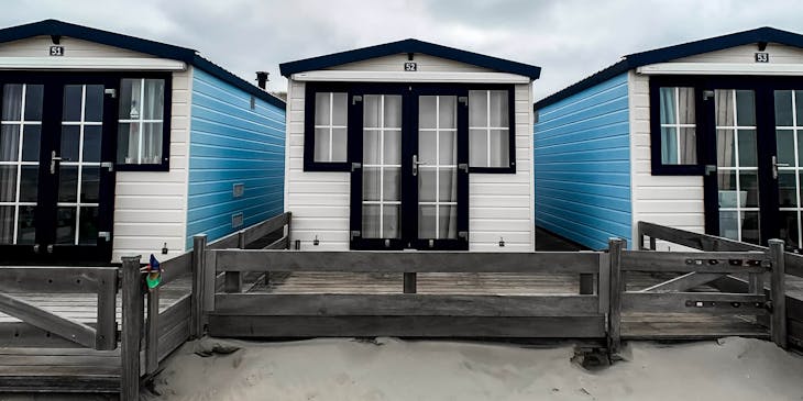 Blue and white mobile homes on sand.