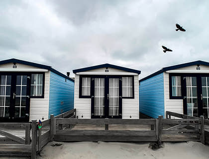 Des mobil-homes bleu et blanc sur le sable.