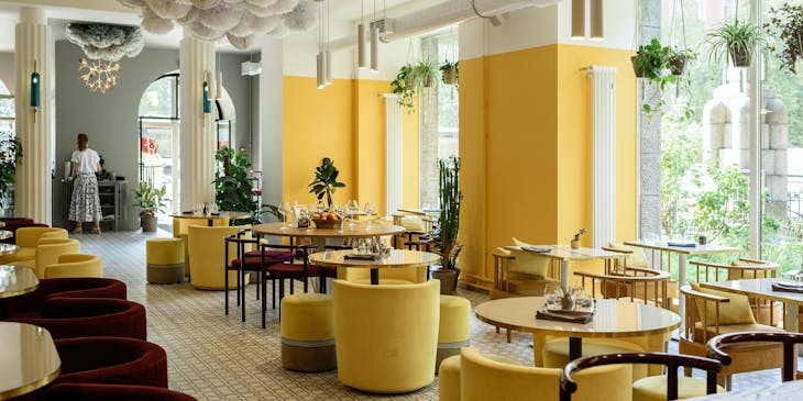The interior of a modern restaurant with yellow decor and big windows.