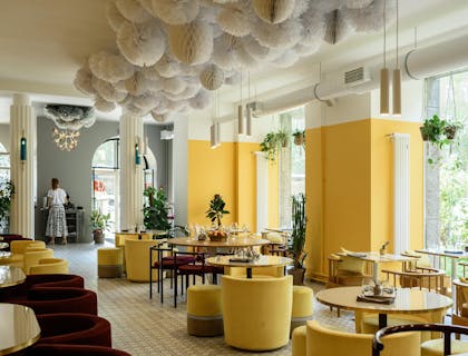 El interior de un restaurante moderno con decoración amarilla y grandes ventanales.