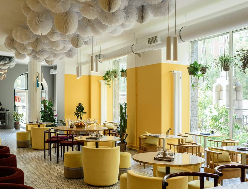 O interior de um restaurante moderno com decoração amarela e grandes janelas.