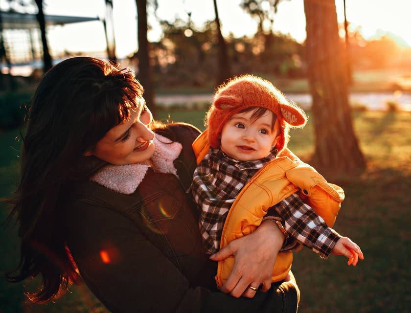 A mom holding a child in a park.