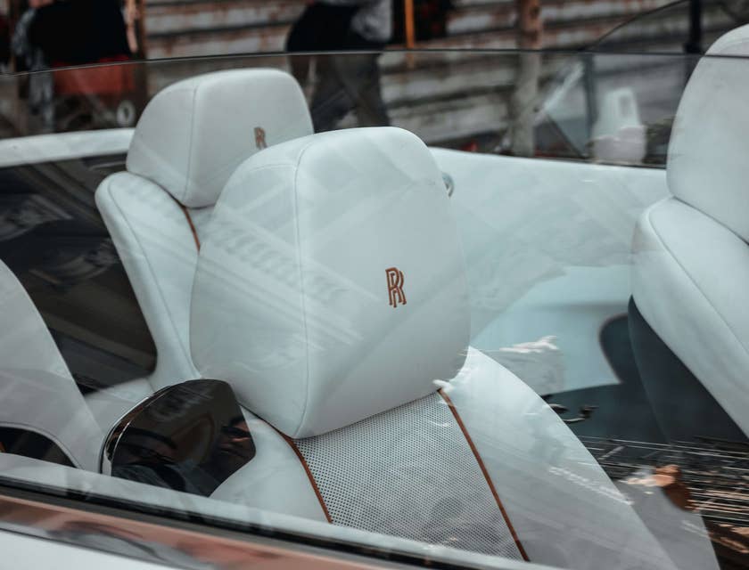 Eine Monogramm-Firma hat ein rotes R auf dem weißen Ledersitz im Innenraum eines Luxusautos angebracht.